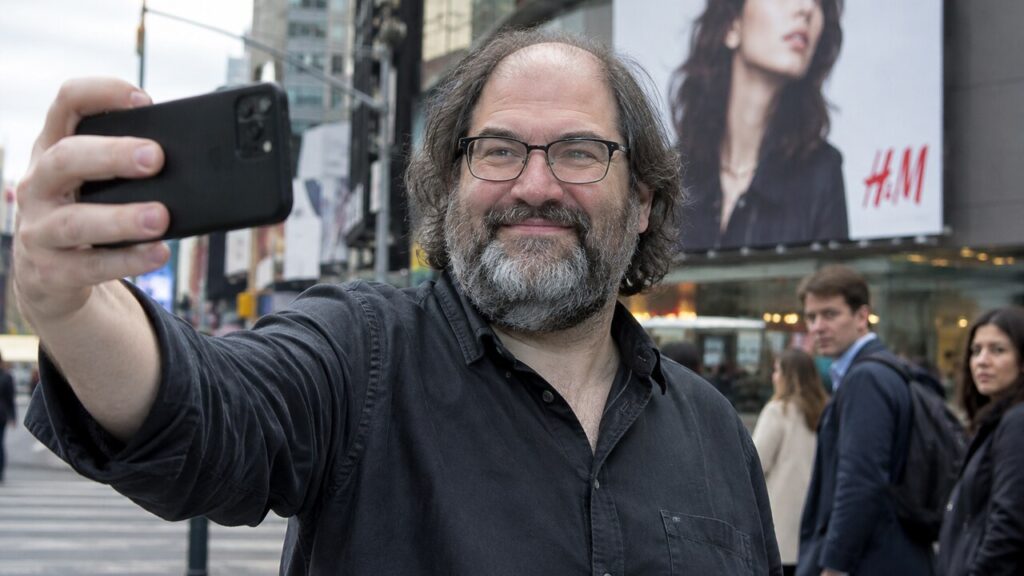 David Schwartz maakt een selfie op straat voor een groot reclamebord