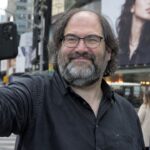 David Schwartz maakt een selfie op straat voor een groot reclamebord
