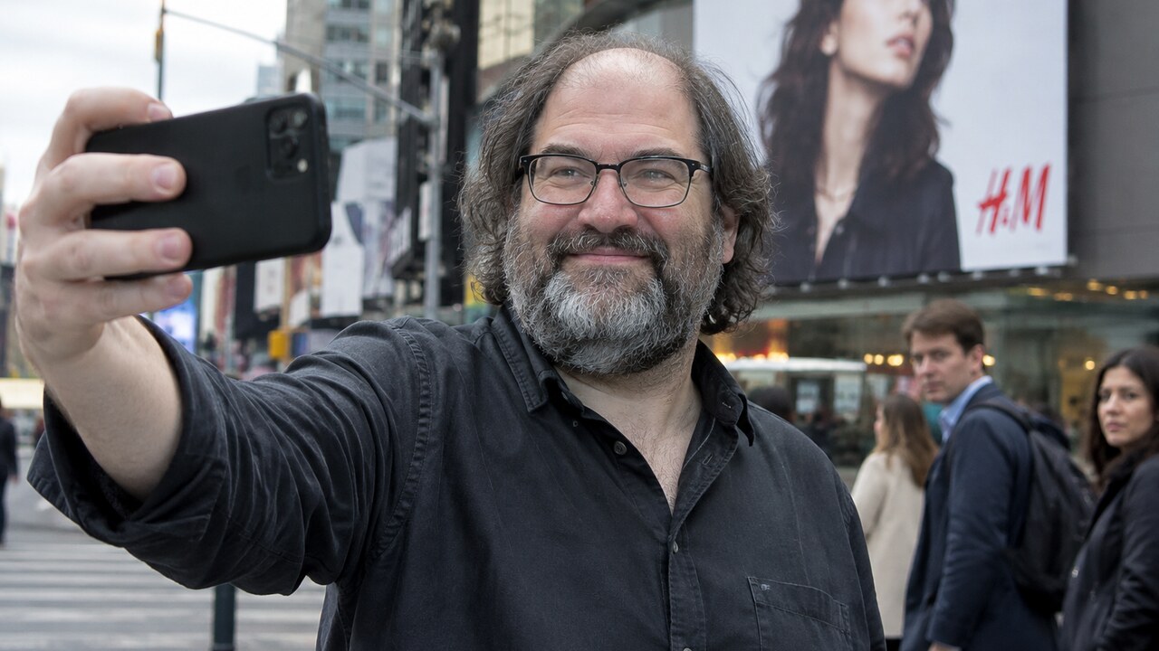 David Schwartz maakt een selfie op straat voor een groot reclamebord