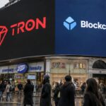 Digitaal reclamebord in een Londense winkelstraat toont het rode Tron-logo naast het Blockchain.com-logo boven voorbijgangers