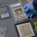 Inbeslaggenomen Pokémonkaarten, Magic-kaarten en een antieke Romeinse munt met bewijslabels op een tafel