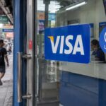 Glazen deur van een geldtransferwinkel in een drukke straat met een groot Visa-logo en een USDC-sticker