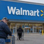 Gevel van een Walmart Supercenter met groot blauw Walmart-logo en klanten met winkelwagens op de parkeerplaats