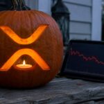 Uitgeholde Halloweenpompoen met het XRP-logo op een veranda, naast een tablet met een dalende rode koersgrafiek