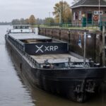 Vrachtschip met groot XRP-logo wacht in een Nederlandse sluis tussen twee gesloten sluisdeuren