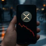 Hand met smartphone op een regenachtig kruispunt, met het XRP-logo en een dalende koersgrafiek op het scherm en een oranje stoplicht op de achtergrond