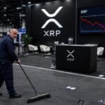 Verlaten XRP-stand op een cryptobeurs met een rode dalende koersgrafiek op het scherm en een schoonmaker die de vloer veegt
