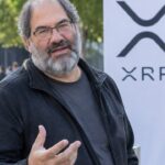 David Schwartz van Ripple in gesprek op een zonnige binnenplaats van een conferentie, met een banier van de XRP Ledger op de achtergrond