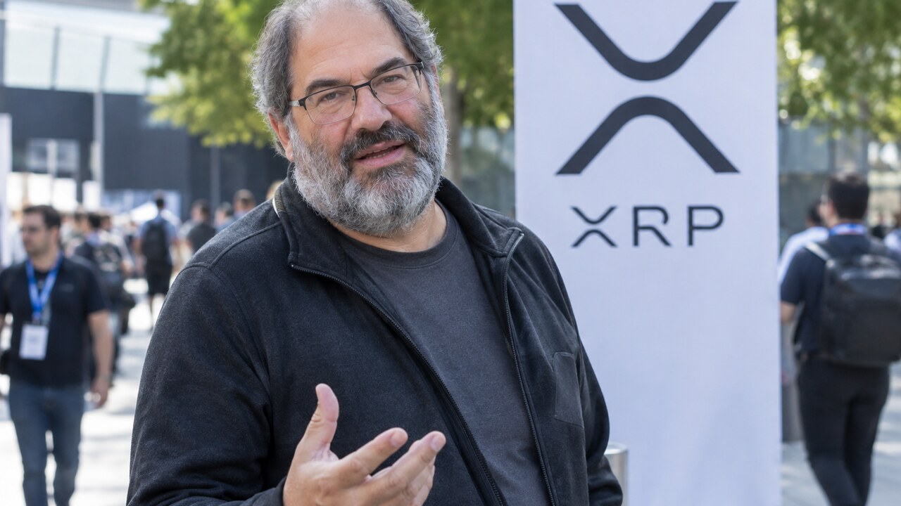 David Schwartz van Ripple in gesprek op een zonnige binnenplaats van een conferentie, met een banier van de XRP Ledger op de achtergrond