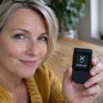 Vrouw aan een keukentafel houdt een hardware wallet vast met het XRP-logo op het scherm