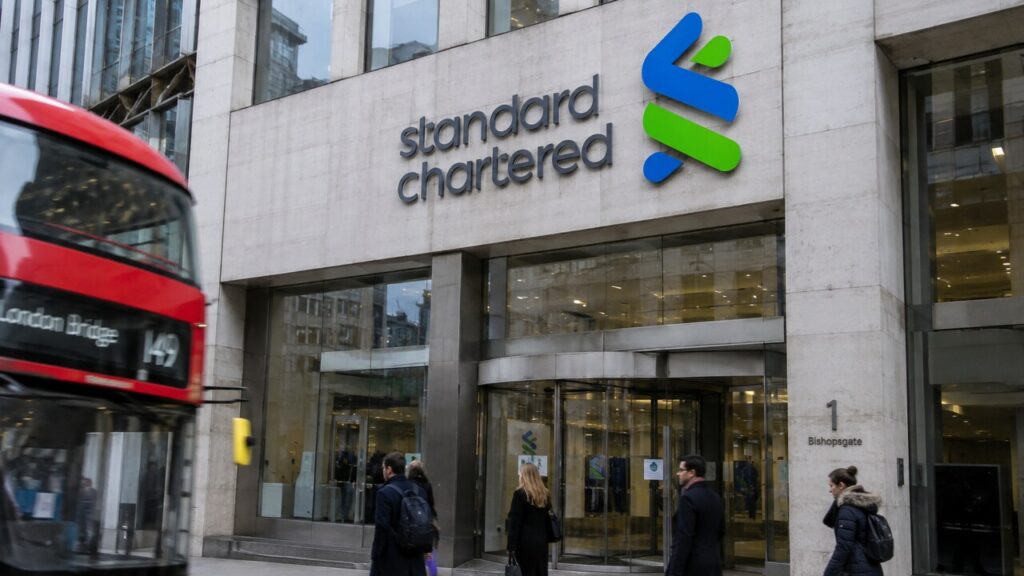 Gevel van het hoofdkantoor van Standard Chartered in Londen met het logo van de bank, voorbijgangers op straat