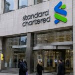Gevel van het hoofdkantoor van Standard Chartered in Londen met het logo van de bank, voorbijgangers op straat
