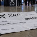 Grote cheque van 250.000 dollar met XRP-logo die verfrommeld op de vloer van een beveiligingsconferentie ligt